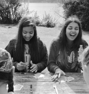 2 girls sitting at picnic table lakeside